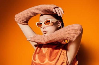 Yaz için özel tasarım koleksiyonu. Moda mankeni kız şık gözlüklerle poz veriyor ve turuncu bir bluzla turuncu bir arka planda. Güneş gözlüğü için moda ve tarz.