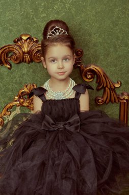 Kabarık siyah bir gece elbisesi ve lüks bir iç mekanda pahalı bir inci kolye giyen güzel bir kız model. İyi akşamlar çocuklar. Giysiler ve mücevherler. Akşam saç stilleri.