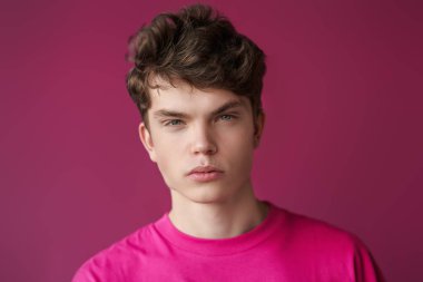 Mor bir arka planda, kırmızı bir kazak içinde, fotokopi uzayı olan ciddi bir modern erkek mankenin portresi. Gençlik modası. Erkek saç stilleri.