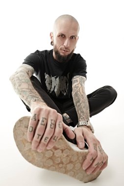 Antisosyal davranış, protesto ifadesi. Ayakları kameraya doğru uzanan gayri resmi görünümlü vahşi bir adam kameraya meydan okuyarak bakar. Beyaz stüdyo geçmişi.