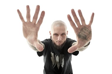 Gayri resmi görünümlü, kafası kazınmış, dudakları ve kulaklarında piercingler olan vücudunda dövmesi olan bir adam avuç içlerini kameraya uzatıyor. Beyaz stüdyo geçmişi.