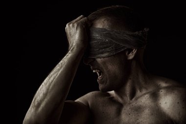 Psikolojik resim. Çıplak gövdeli, iri yarı, güçlü bir adam sargı beziyle gözlerini kapatır ve bağırır. Fotokopi alanı olan siyah bir arkaplanda stüdyo portresi.