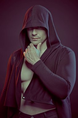 Dövüşçü. Güçlü, kendine güveni olan atletik yapılı bir adam gözlerini kaputun altında gizliyor. Stüdyo portresi. Güç sporları, sağlık ve aktif yaşam pozisyonu. Boksör.