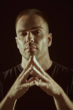 Yakışıklı kaslı bir adam sakince kameraya bakar. Siyah arka planda stüdyo portresi. İnsanlar ve duygular. Yaşam tarzı, seçimler. Spor..