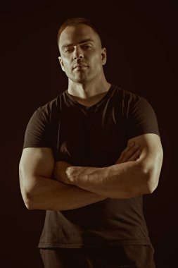 Sporcu, vücut geliştirici. Güçlü bir adam kameraya özgüvenle bakar. Siyah arka planda stüdyo portresi. Yaşam tarzı. Spor..