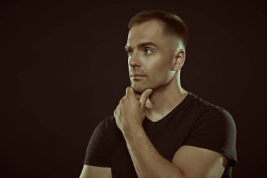 Atletik yapılı yakışıklı ve güçlü bir adam sakin ve kendinden emin duruyor. Metin için alanı olan siyah arkaplan. İnsanlar ve duygular. Aktif, sağlıklı bir yaşam tarzı. Spor..