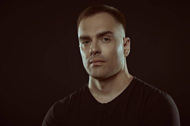 İnsanlar ve duygular. Atletik yapılı, yakışıklı, güçlü bir adamın portresi. Metin için alanı olan siyah arkaplan. Aktif, sağlıklı bir yaşam tarzı. Spor..