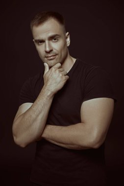 Yaşam tarzı. Sporcu, vücut geliştirici. Güçlü bir adam sakince ve kendinden emin bir şekilde kameraya bakar. Siyah arka planda stüdyo portresi. Spor..