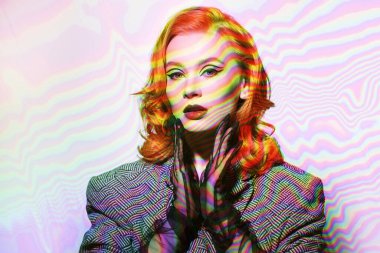 Beyaz stüdyo arka planında ceketli ve şifon eldivenli çekici kızıl saçlı bir kadının portresi. Zarif oklarla makyaj yapın. Hollywood dalgası saç stili. Zarif retro tarzı ve modası.