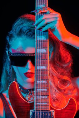 Siyah arka planda elektro gitaristle poz veren bir kız rock gitaristi portresi. Şarkıcı, müzisyen.