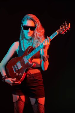 Şarkıcı, müzisyen. Siyah arka planda elektro gitaristle poz veren bir kız rock gitaristi portresi.. 
