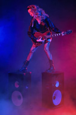 Glam rock tarzı. Parlak bir rock yıldızı müzisyen kız sahnede duruyor ve seyirciye gülümsüyor. Rock gitaristi, şarkıcı.