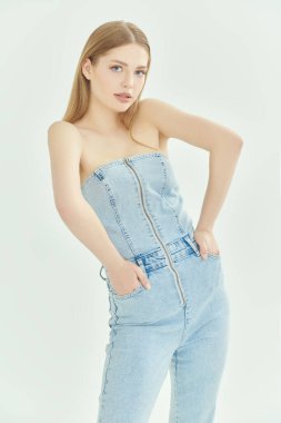 Gençlik kotu modası. Yazlık kıyafetler. Sarışın, güzel bir manken kız çıplak omuzlu, modaya uygun bir kot giyip poz veriyor. Beyaz stüdyo geçmişi.