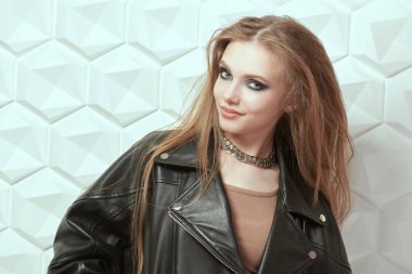 Koyu renkli dumanlı gözlü, uzun taraklı saçlı. Beyaz stüdyo arka planında poz veren çekici rock yıldızı genç kız. Modern gençlik pop ve rock kültürü.