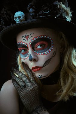 Siyah arka planda Calavera Atrina makyajı olan güzel ve korkutucu bir kızın portresi. Ölüler Günü 'nün sembolü. Cadılar Bayramı. Kafatası şekeri kız. Dia de los Muertos.