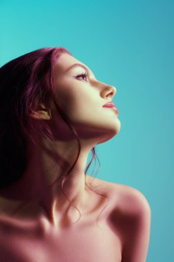 Kadın güzelliği ve sağlığı. Zarif makyajlı ve saç stili olan ince bir kızın profil portresi. Yumuşak mavi arka plan. Cilt bakımı. Kozmetik ürünleri ve makyaj. 