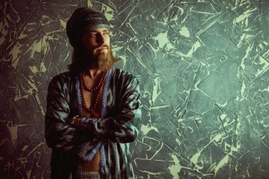 Hippi rastaman görünümlü bir adam kollarını göğsüne katlamış ve hafifçe gülümsüyor. Kopyalama alanı ile Grunge arkaplanı.