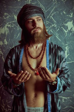 Hippi rastaman görünümlü bir adam kollarını göğsüne katlamış ve hafifçe gülümsüyor. Grunge arkaplanı.