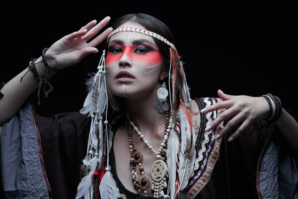 Portrait of a beautiful American Indian girl in traditional dress and jewelry on a black background. 