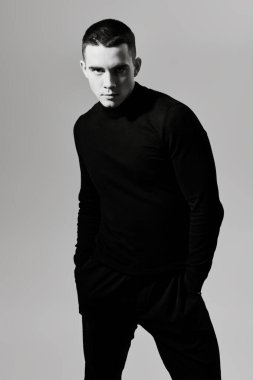 Kısa saçlı, siyah elbiseli, beyaz bir stüdyoda poz veren yakışıklı bir gencin siyah beyaz portresi. Bir adamın psikolojisi..