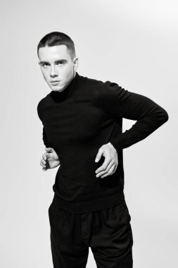 Kısa saçlı, siyah elbiseli, beyaz bir stüdyoda poz veren yakışıklı bir gencin sanat portresi. Siyah beyaz portre. Bir adamın psikolojisi..