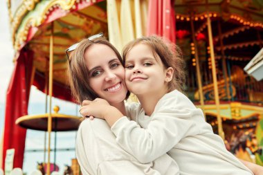 Küçük bir kız annesiyle bir lunaparkta. Yaz tatili ve tatil. Mutlu aile.