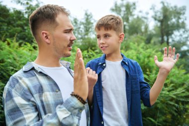 Dost canlısı baba ve oğul bir yaz parkında beklerken beş dolar veriyor. Mutlu bir aile. Yaz zamanı ve tatil.