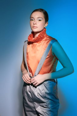 Geniş paçalı pantolon ve pantolon giymiş şık bir manken. Stüdyoda karışık renkli ışıkta en üstte. Parlak renkler. Yeni moda koleksiyon. Tasarımcı kıyafeti.