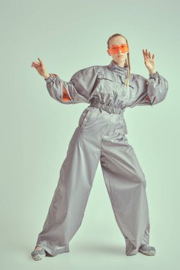 Beyaz bir stüdyo arka planında gri bir takım elbiseyle poz veren güzel bir kadın mankenin tam boy portresi. Yüksek moda. Gelecekçi Moda Biçimi.