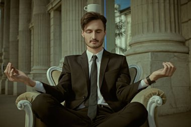 Takım elbiseli genç bir adam şehir caddesinde bir koltukta oturuyor. Sakinlik ve güven kavramı. 