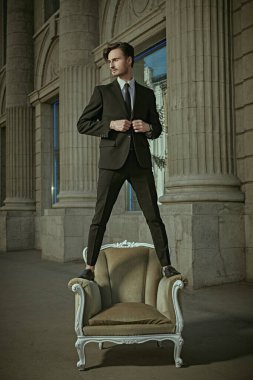 Başarı. Başarılı ve kendine güvenen takım elbiseli genç bir adam şehrin sokaklarında bir koltukta duruyor. Sakinlik ve kendine güven kavramı.. 