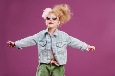 Tatil günü. Kot ceketli, pembe güneş gözlüklü ve modaya uygun saç stili olan güzel bir moda kızı portresi. Kopya alanı ile Stüdyo fuşya arkaplanı.