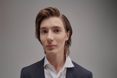 Modern eğitim. İnsanlar ve duygular. Klasik takım elbiseli, meraklı bir gencin portresi. Gri stüdyo geçmişi.