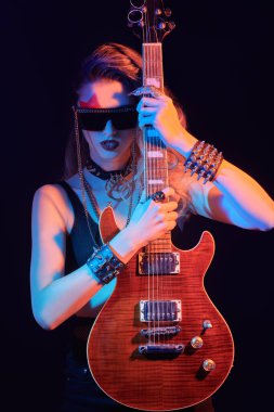 Siyah arka planda elektro gitaristle poz veren bir kız rock gitaristi portresi. Şarkıcı, müzisyen.
