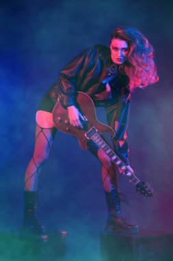 Rock gitaristi, şarkıcı. Parlak bir rock yıldızı müzisyen kız sahnede duruyor. Glam rock tarzı.