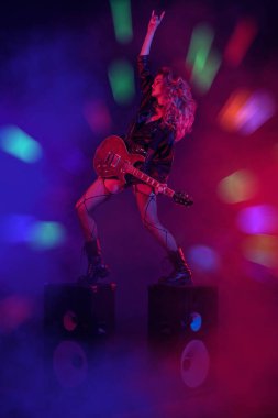 Glam rock tarzı. Parlak bir rock yıldızı müzisyen kız sahnede duruyor ve seyirciye gülümsüyor. Rock gitaristi, şarkıcı.