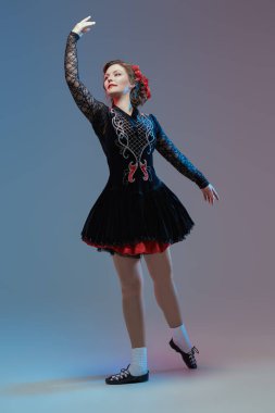 Ulusal İrlanda kostümü giymiş profesyonel bir dansçı kadının geleneksel İrlanda dansını sergilediği bir stüdyo resmi..