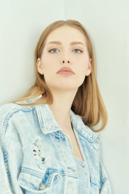 Kadın güzelliği. Beyaz bir stüdyo arka planında kot ceketli güzel sarışın bir kızın portresi. Denim modası.