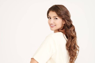 İnsanlar, mutlu duygular. Uzun kıvırcık saçlı, mutlu ve heyecanlı bir şekilde gülümseyen güzel bir kızın portresi. Fotokopi alanı olan beyaz stüdyo. Kadın güzelliği.