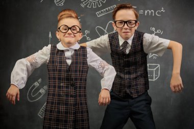 Sevimli küçük okul çocukları siyah karatahta arka planında komik poz veriyorlar. Eğitim ve erken gelişim. Küçük Bilim adamları.