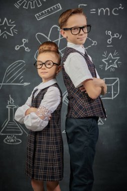Küçük şirin okul çocukları siyah karatahta arka planında poz veriyorlar. Eğitim ve erken gelişim. Küçük Bilim adamları.