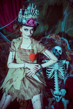 Voodoo büyüsü. Esrarengiz ve korkutucu bir kızın portresi voodoo bebeği gibi giyinmiş, kasvetli eski bir evde örümcek ağlarıyla kaplı duruyor. Cadılar Bayramı.