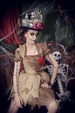 Voodoo büyüsü. Esrarengiz ve korkutucu bir kızın portresi voodoo bebeği gibi giyinmiş, kasvetli eski bir evde örümcek ağlarıyla kaplı duruyor. Cadılar Bayramı.