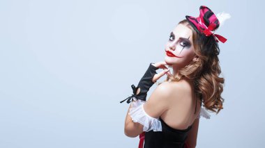 Beyaz arka planda güzel ve korkutucu genç bir palyaçonun portresi. Makyaj ve saç stili. Cadılar Bayramı karakteri. Güzellik ve Korku. Metin için boşluk.