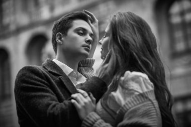 Aşk hikayesi. Gençler ve ilişkiler. Birbirlerine aşık genç ve mutlu bir çift şehrin sokaklarında dikilirken birbirlerine sarılıyorlar. Bulutlu bir günde yürümek. Siyah-beyaz çekim.