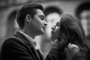 Aşk hikayesi. Gençler ve ilişkiler. Birbirlerine aşık genç ve mutlu bir çift şehrin sokaklarında dikilirken birbirlerine sarılıyorlar. Bulutlu bir günde yürümek. Siyah-beyaz çekim.