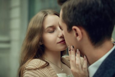 Gençler ve ilişkiler. Şehir caddesinde dururken birbirini öpen mutlu genç çift. Bulutlu bir günde yürümek. Aşk hikayesi..