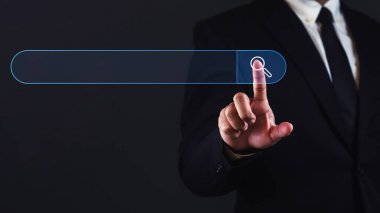 İş adamı karanlık arkaplana karşı metin için boş alan ile sanal arama çubuğuna dokunuyor.