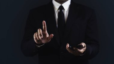 İşadamı akıllı telefon kullanıyor, işaret ediyor ya da dokunuyor koyu mavi arka plana karşı bir şey seçiyor..