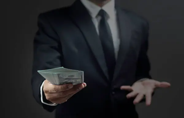 Close up of a business man is holding banknotes against dark background.